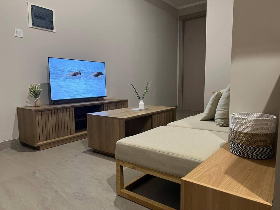 a living room with a flat screen tv and a bed at 2BR JIExpo Menara Jakarta (new) in Jakarta