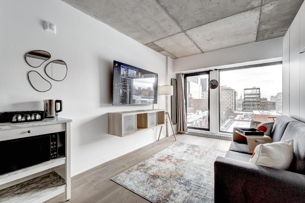 ein Wohnzimmer mit einem Sofa und einem großen Fenster in der Unterkunft Magnifique Studio au centre-ville à 5 min à pied de tout in Montreal
