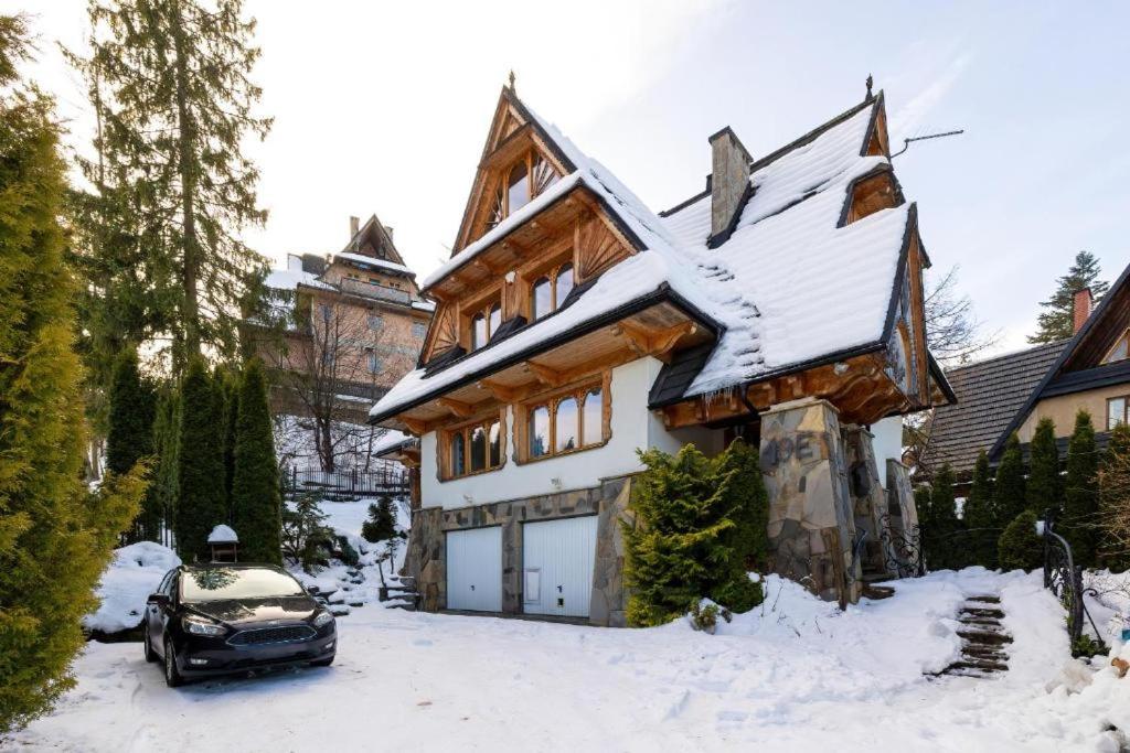 un coche aparcado frente a una casa cubierta de nieve en Apartament Jaszczurówka, en Zakopane