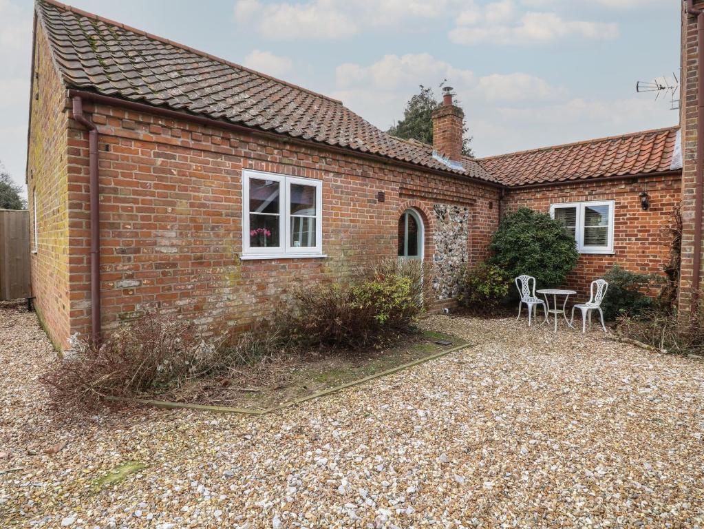 a brick house with two chairs and a table at The Annexe in Fakenham