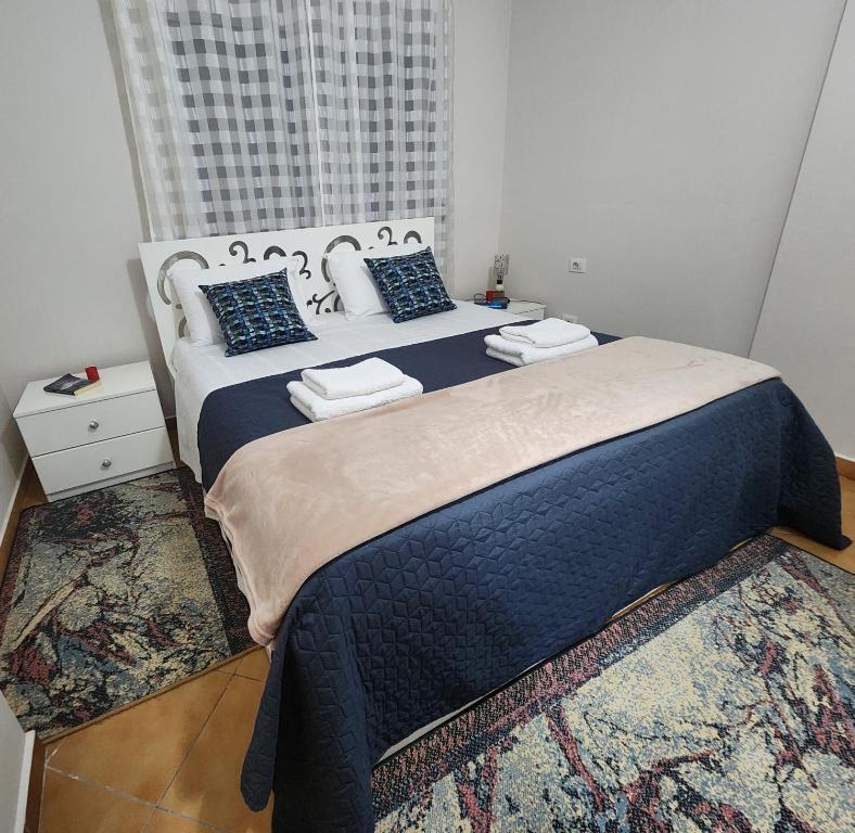 ein Schlafzimmer mit einem großen Bett mit blauer Bettwäsche und Kissen in der Unterkunft cancel in Tirana