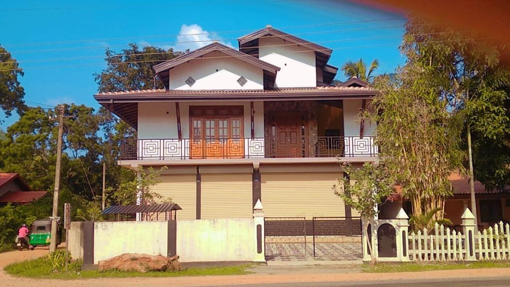 a house with a white fence in front of it at Arana Holiday Resort in Kurundankulama