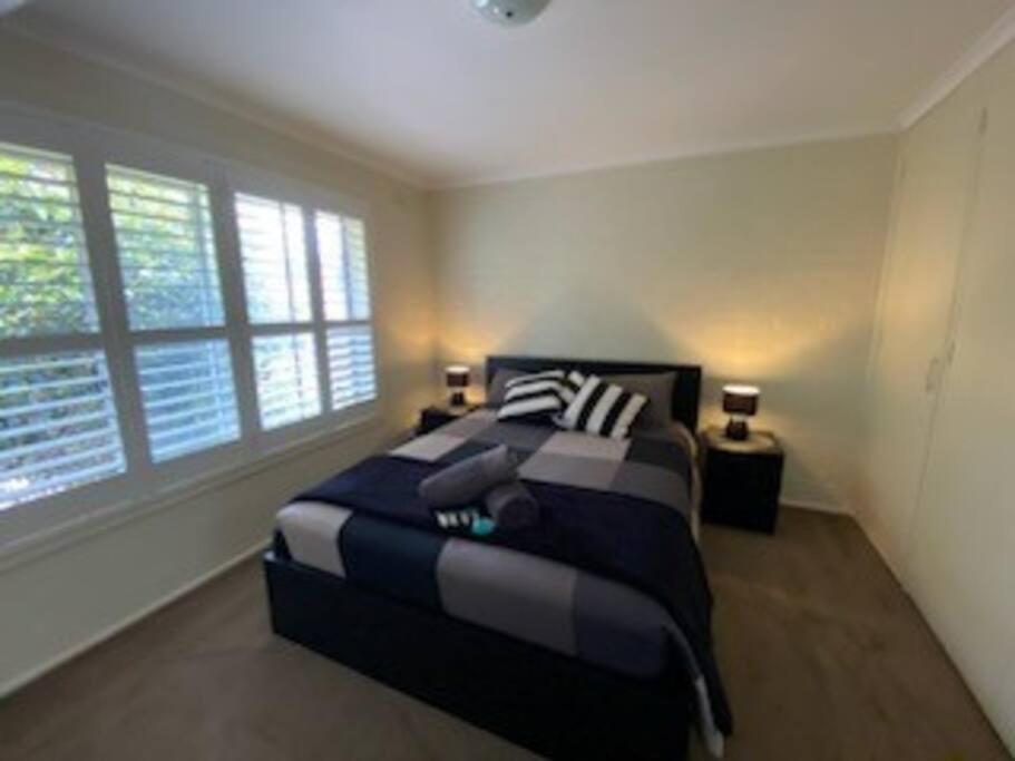 a bedroom with a large bed with two windows at Self contained 2 bedroom unit in Williamstown