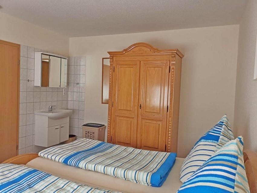 a bedroom with a bed and a wooden cabinet at Ferienwohnung Haus Waldesrand in Norderney