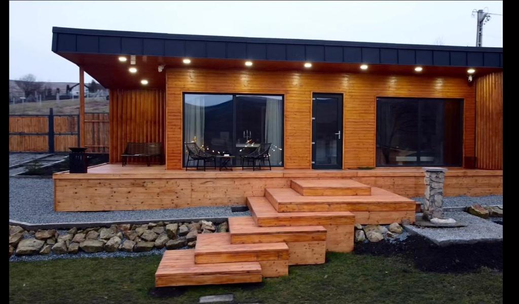 a house with a deck with a table and benches at Story Cabin Lake in Cîmpeneşti