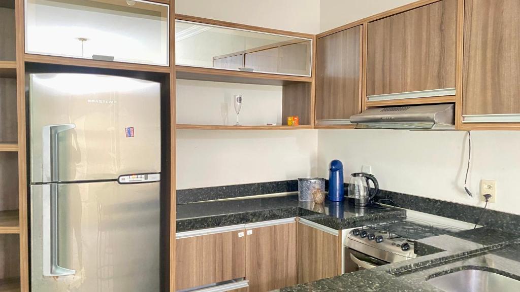 a kitchen with wooden cabinets and a stainless steel refrigerator at Casa de 2 QUARTOS COM PISCINA in Balneário Camboriú