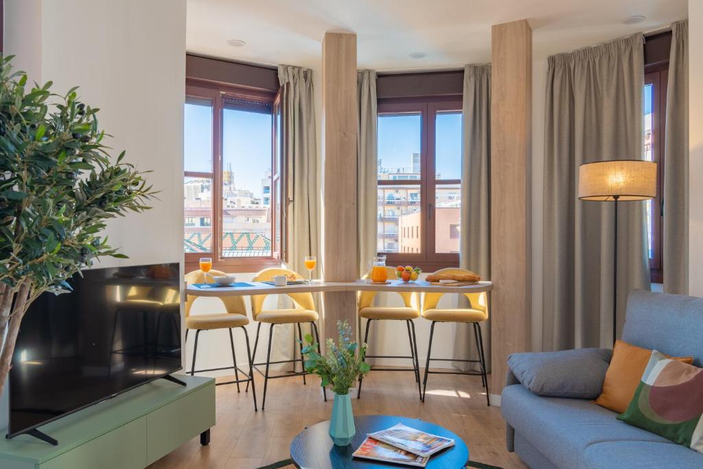 Hotel Feelathome Atarazanas Apartments, a living room with a couch and a table with chairs at Feelathome Atarazanas Apartments in Málaga