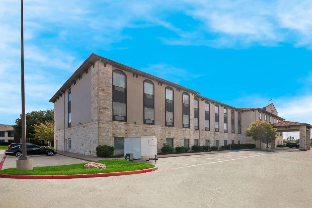 a large brick building with a car parked in a parking lot at Comfort Suites Granbury in Granbury