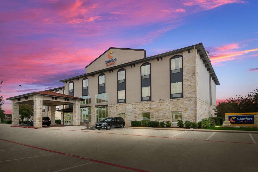 a building with a car parked in front of it at Comfort Suites in Granbury