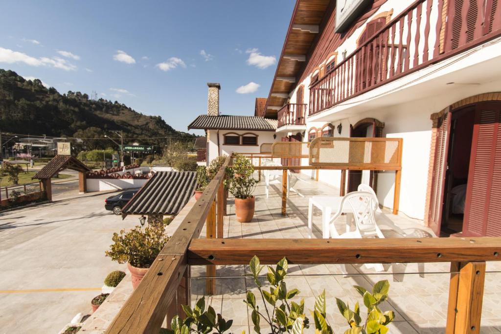 uma varanda de um edifício com duas cadeiras brancas em Hotel JB em Campos de Jordão