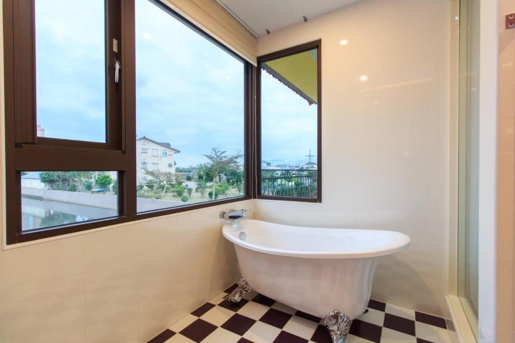 a bath tub in a bathroom with windows at Elegance House in Wujie