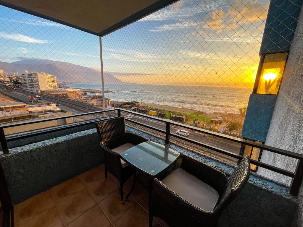balkon ze stołem i krzesłami oraz widokiem na ocean w obiekcie Departamento Los Delfines w mieście Iquique