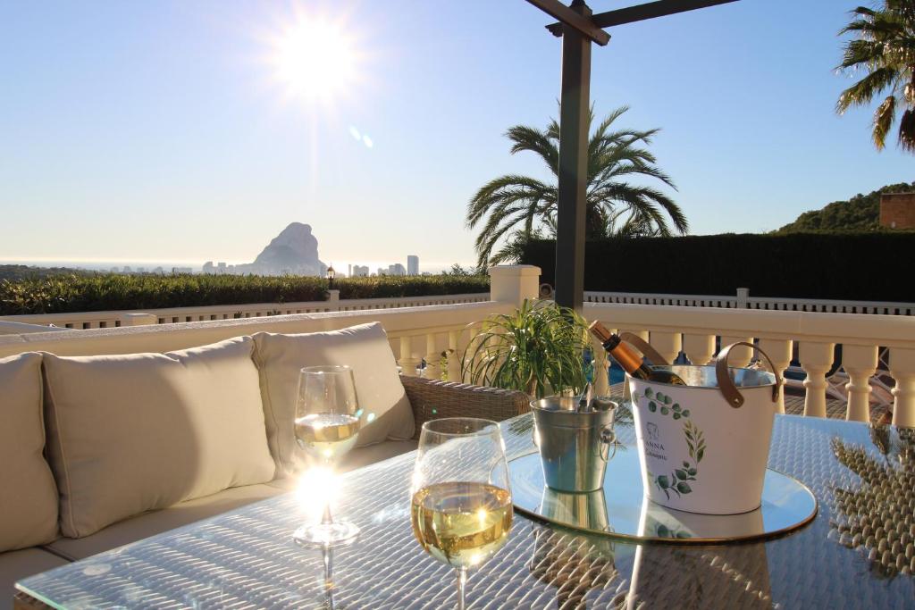 una mesa con copas de vino en el balcón en Ty Croeso-Entire villa with sea view, en Calpe