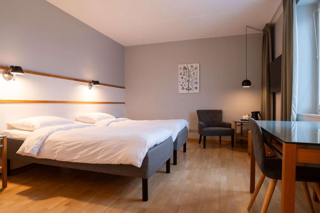 a bedroom with two beds and a desk and a table at Best Western Plus Park City Solna in Solna