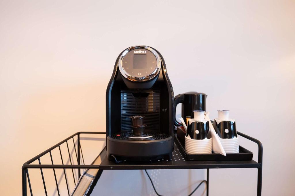 a black coffee maker on a shelf with cups at Best Western Plus Park City Solna in Solna