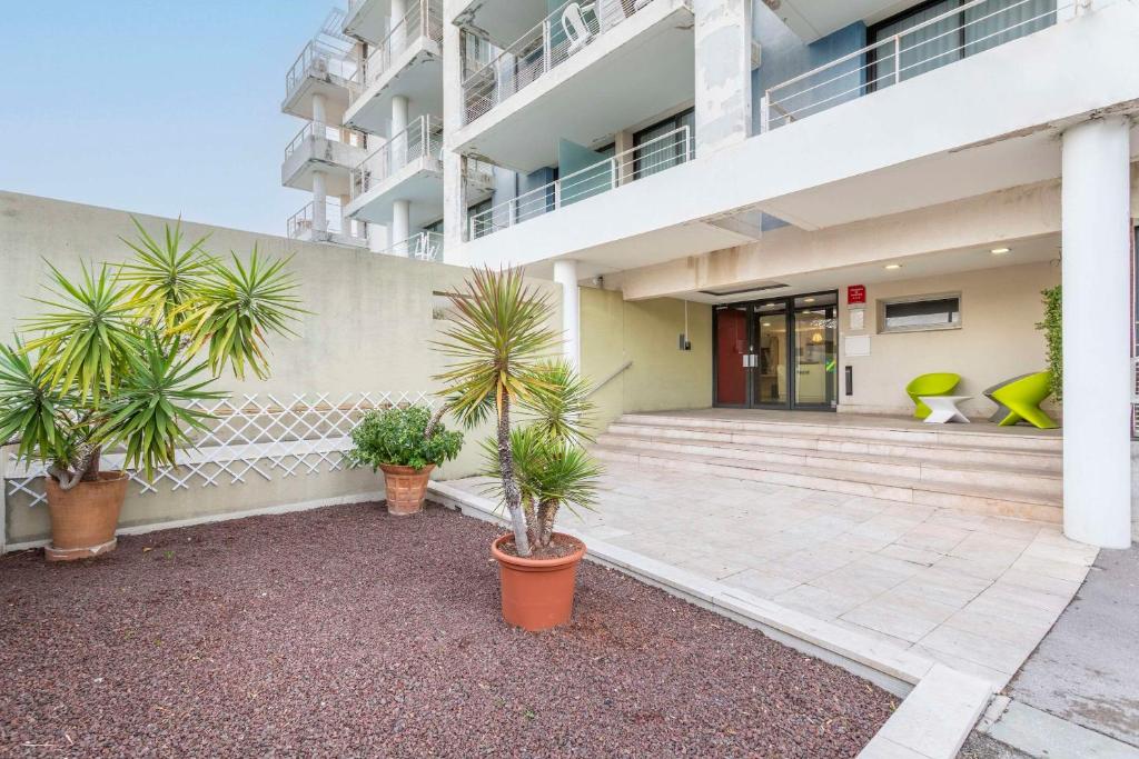 un bâtiment avec des palmiers en face de celui-ci dans l'établissement Zenitude Hôtel-Résidences - Marseille Prado Plage, à Marseille