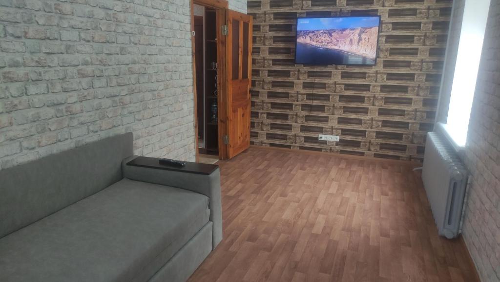a living room with a couch and a tv on a brick wall at Cozy apartment near city center on Peremogy Avenue 44, bus and railway station nearby in Chernihiv