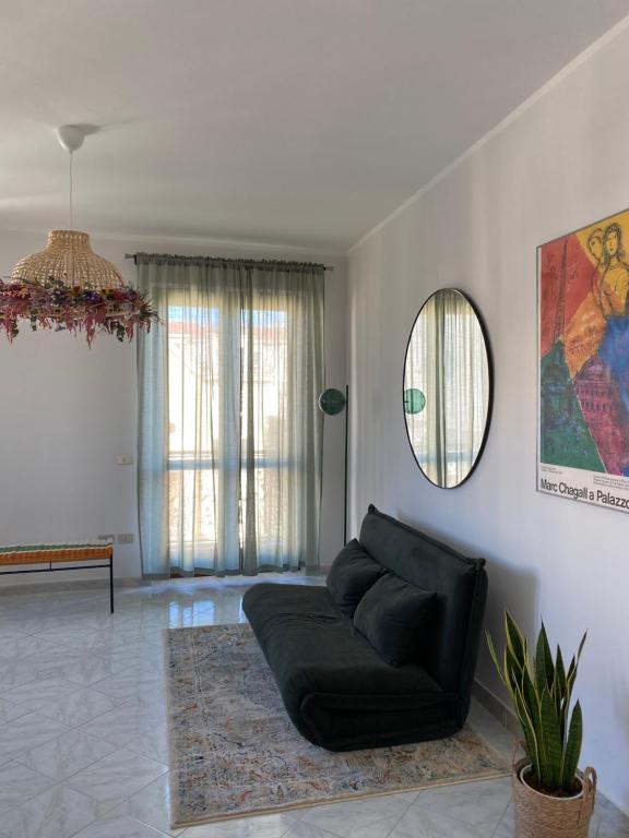 sala de estar con sofá negro y espejo en NICE - camere con bagno privato, en Lioni