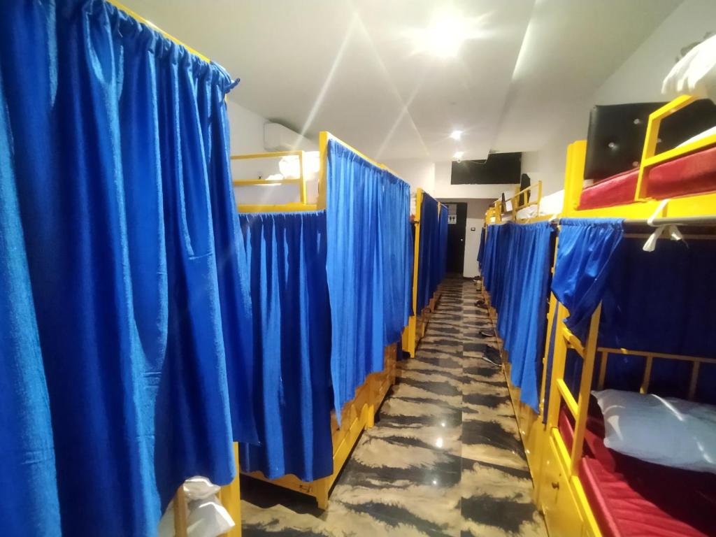 a row of bunk beds in a room with blue curtains at New Mango Dormitory in Mumbai