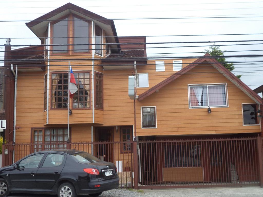 un coche negro estacionado frente a una casa de madera en Hostal Lagunitas, en Puerto Montt