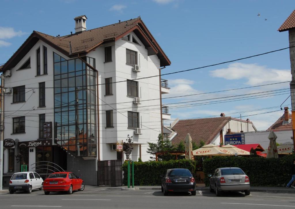 une maison blanche avec des voitures garées devant elle dans l'établissement Pensiunea Turistica Europa, à Drobeta-Turnu Severin