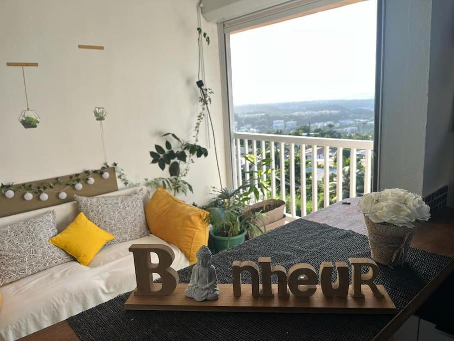 een kamer met een bank en een balkon met een bordje dat last geeft bij Le Mangot du Bonheur avec vue imprenable in Fort-de-France