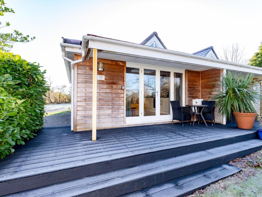 a small wooden house with a table on a deck at Pass the Keys Stylish Garden cottage in Wells, Somerset in Wells