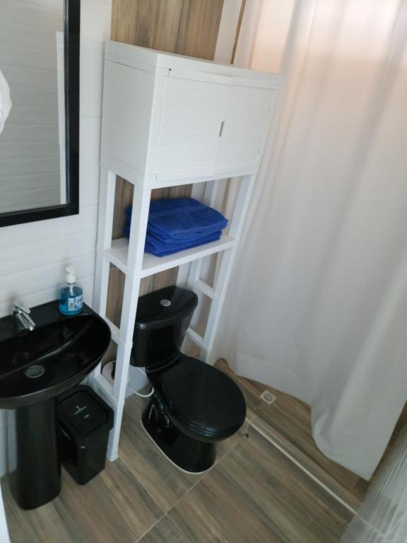 baño con aseo negro y lavamanos en Sea Breeze inn 102, en Providencia