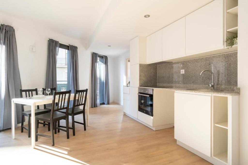 uma cozinha com armários brancos e uma mesa e cadeiras em Centric Apartment Camp Nou em L'Hospitalet de Llobregat
