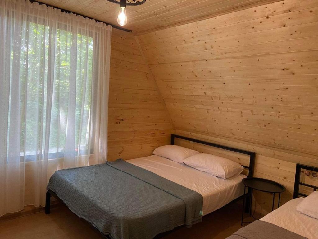 um quarto com uma cama num chalé de madeira em 3 bedroom cottage in Bobokvati em Boboqvat'i