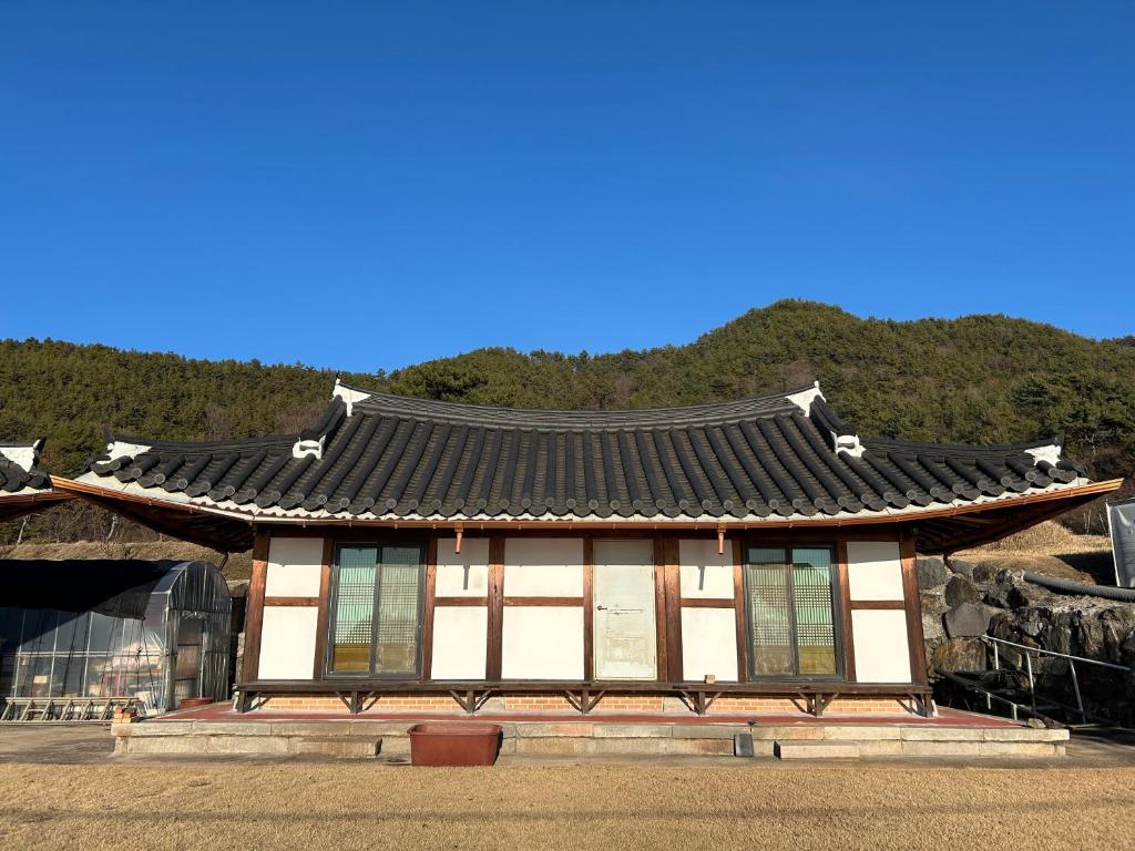 a building with a roof in front of a mountain at Sunset Hanok Stay in Suncheon
