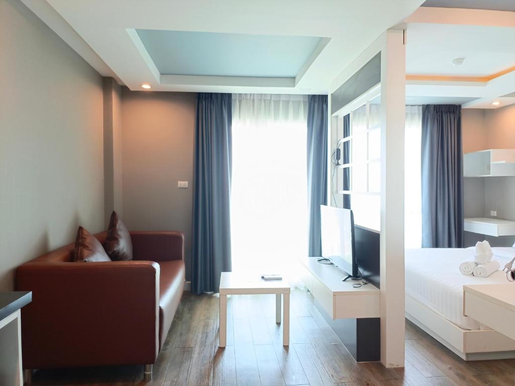 a room with a bed and a couch and a television at Wisdom Hotel & Residence in Rayong