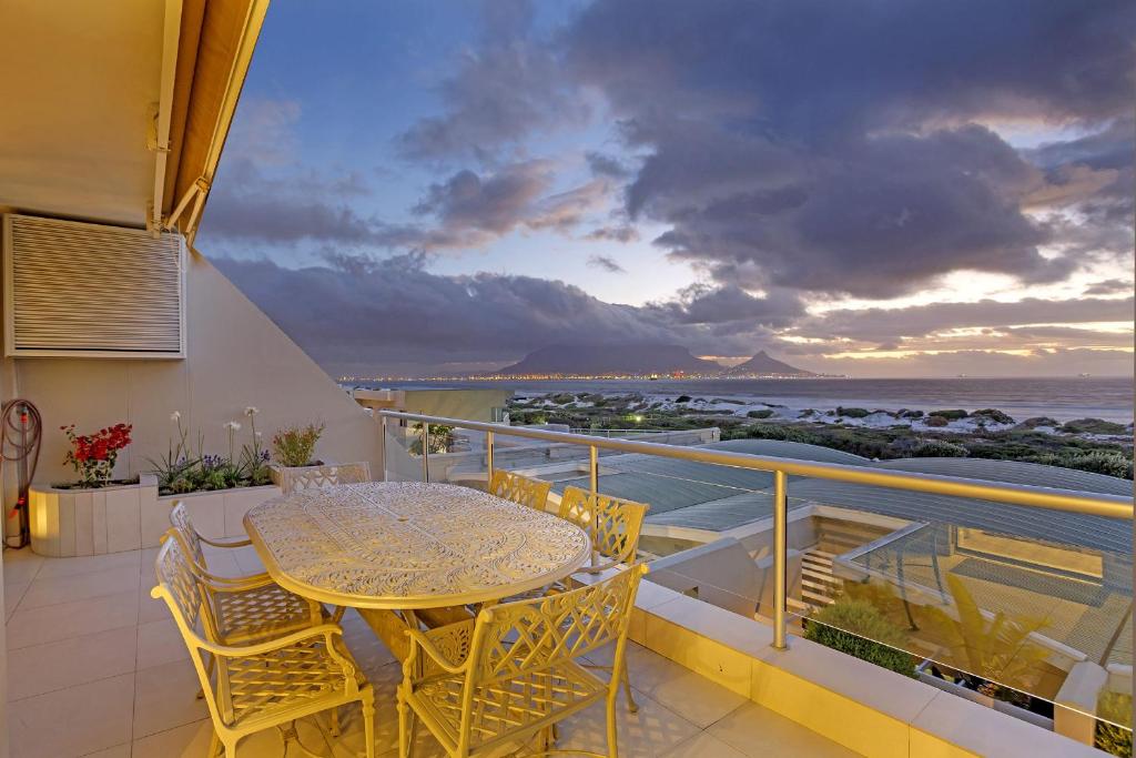 a balcony with a table and chairs and the ocean at Dolphin Beach H106 by HostAgents in Bloubergstrand