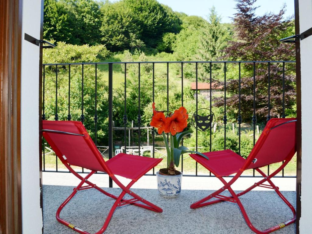 - deux chaises rouges sur une terrasse couverte avec un vase fleuri dans l'établissement Apartment Sambucco - SBO102 by Interhome, à Savone