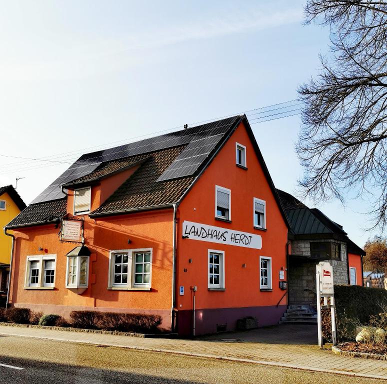 ein orangefarbenes Gebäude mit schwarzem Dach auf einer Straße in der Unterkunft Landhaus Herdt in Lauda-Königshofen