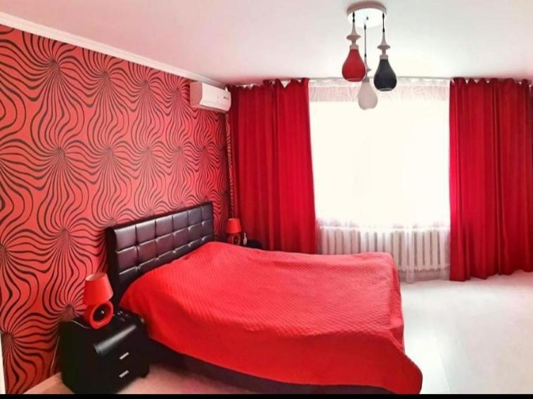 1 cama roja en un dormitorio con cortinas rojas en Stylish apartment on street Ismail 84, en Chişinău