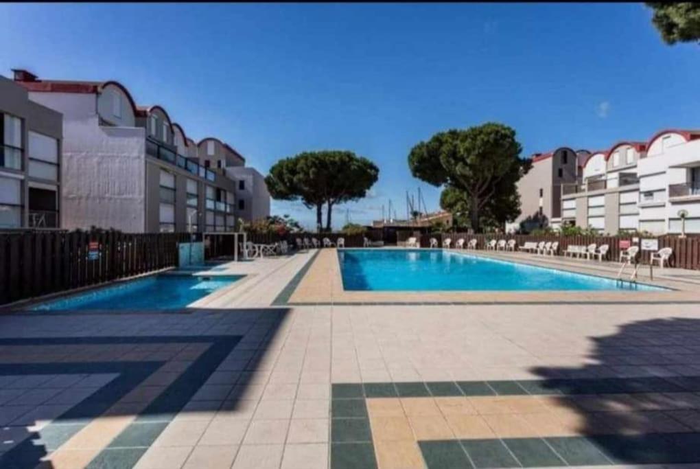 - une piscine avec des chaises, des arbres et des bâtiments dans l'établissement studio avec piscine, à Gruissan