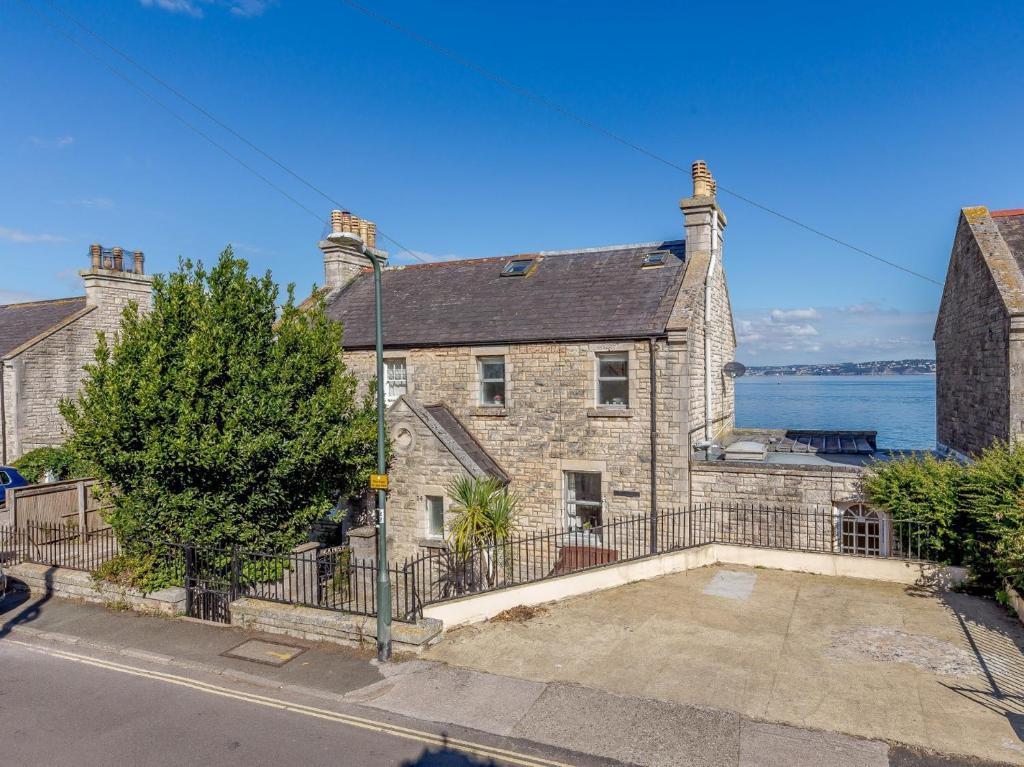 an old stone house with a fence in front of the water at 3 Bed in Brixham BX007 in Brixham