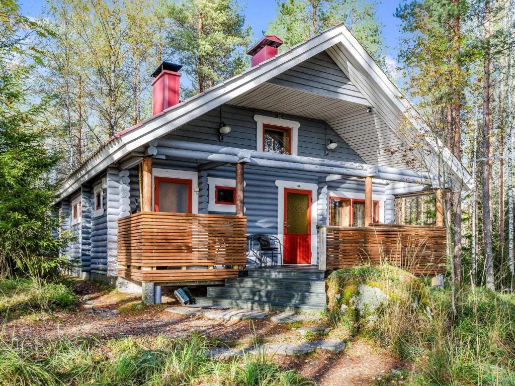 a gray house with a red door in the woods at Holiday Home Ulpukka by Interhome in Savilahti