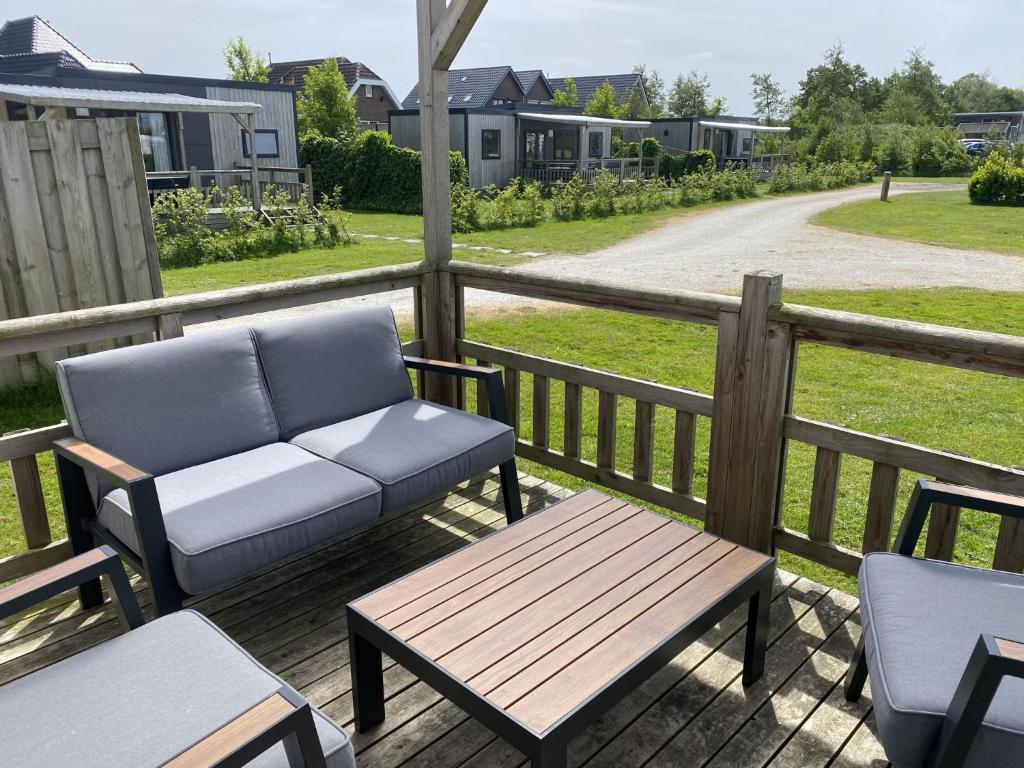 a porch with a couch and a table and a bench at Holiday Home Natuurlijk de Veenhoop by Interhome in De Veenhoop