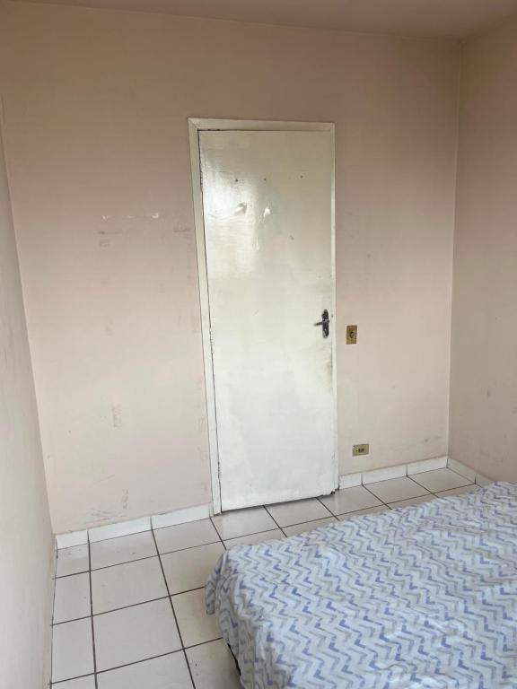 een witte kamer met een bed en een deur bij QUARTO PRIVADO PARA ALGUEL (Diária). in Goiânia