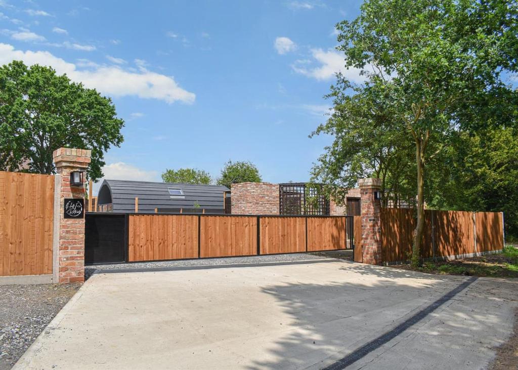 a driveway with a wooden gate and a fence at Hill Farm Retreat in Wangford