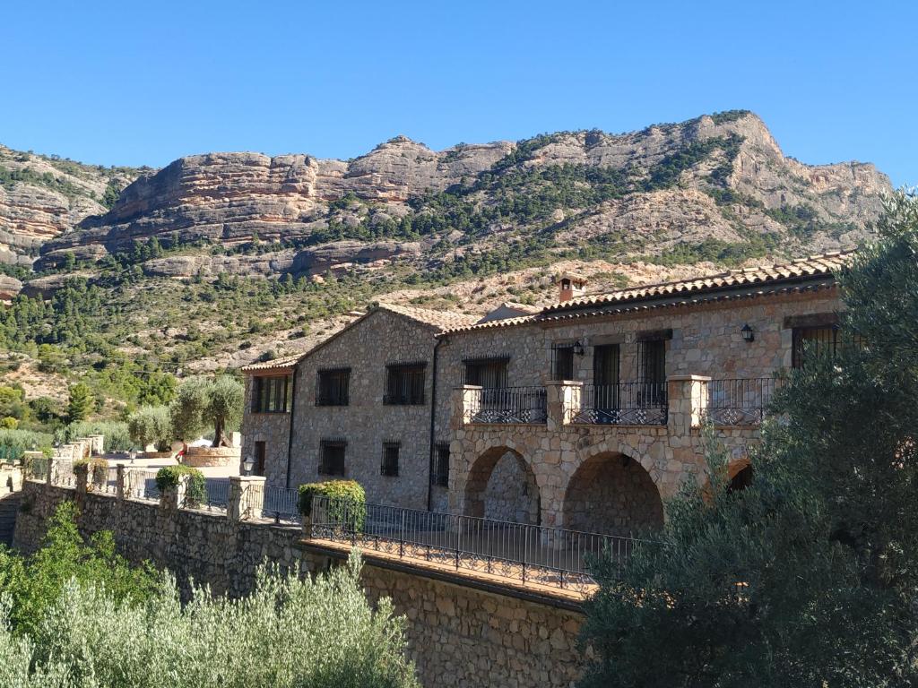 un antiguo edificio de piedra con una montaña en el fondo en Mas de la Vall del Frare, en Gandesa