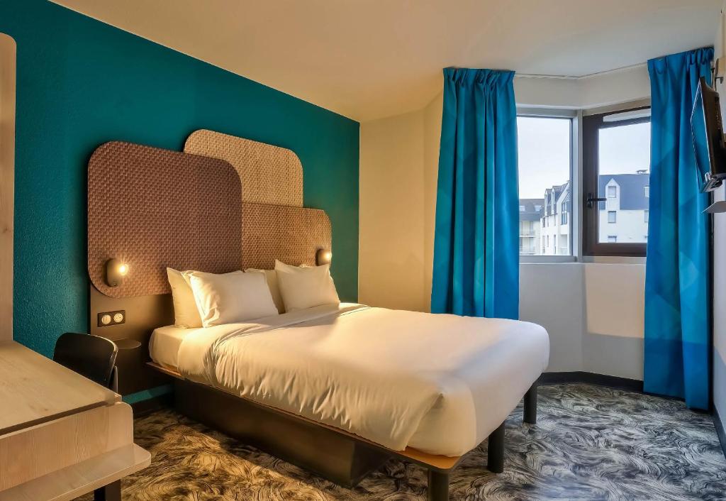 a bedroom with a bed with blue walls and a window at B&B HOTEL Paris Porte de Châtillon in Châtillon