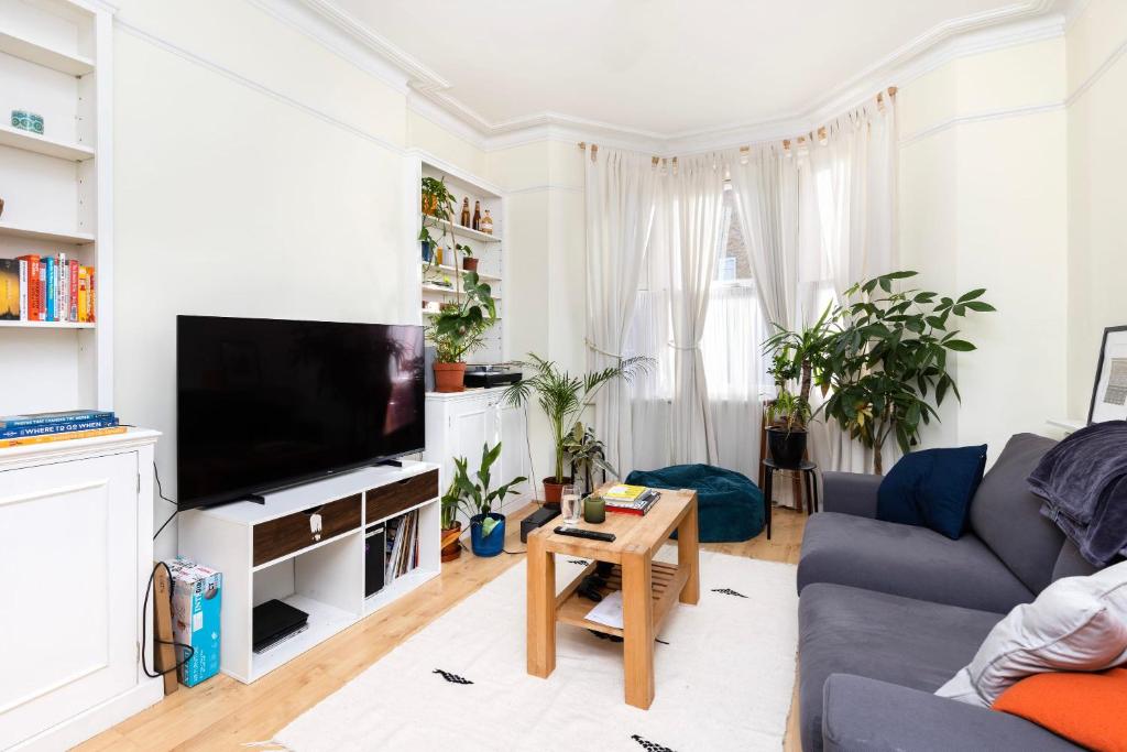 sala de estar con sofá y TV en Charming Victorian 1BR Retreat in the Heart of London, en Londres