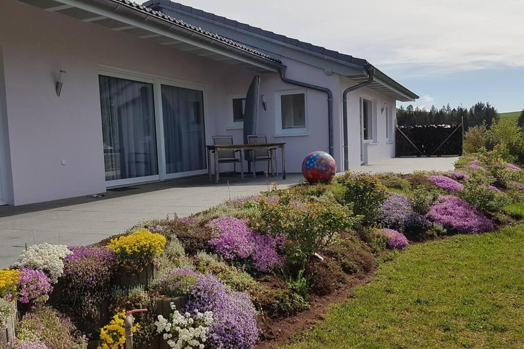 a house with flowers in front of a yard at Das Ferienhaus mit lichtem 85m² Studio in Herrischried