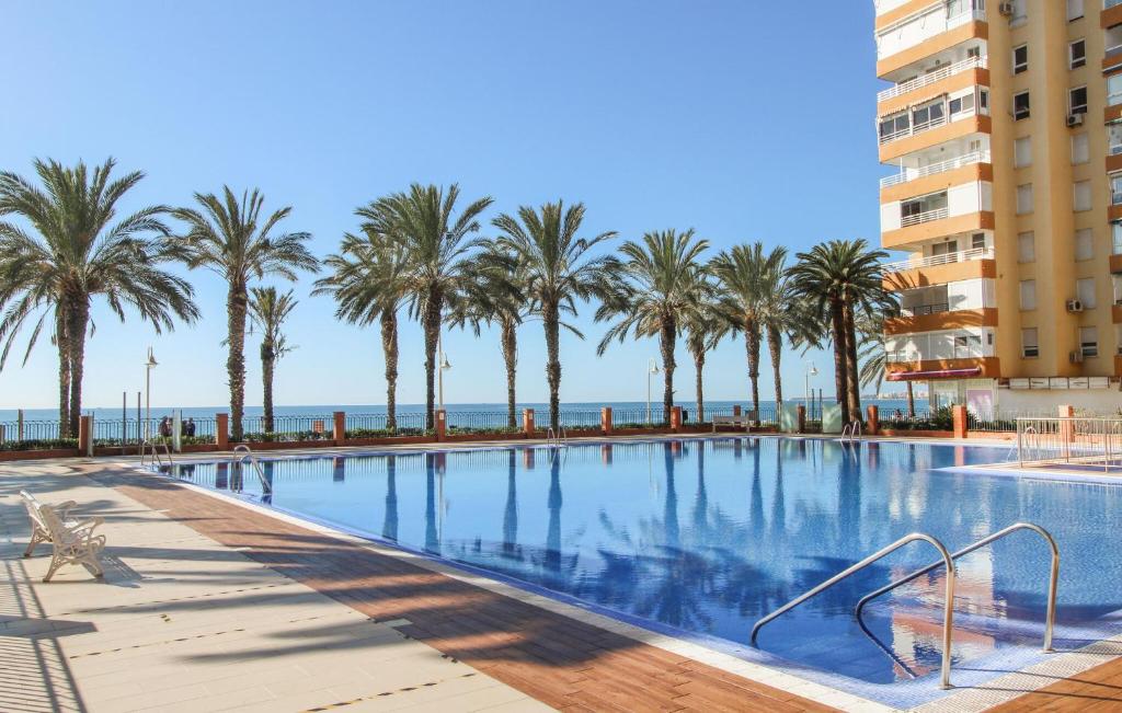 ein Pool mit Palmen und ein Gebäude in der Unterkunft Beach Front Apartment In Algarrobo-costa With Outdoor Swimming Pool in Algarrobo-Costa