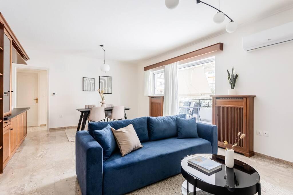 un soggiorno con divano blu e tavolo di Faliro Sunlit 3BR Apartment by UPSTREET ad Atene