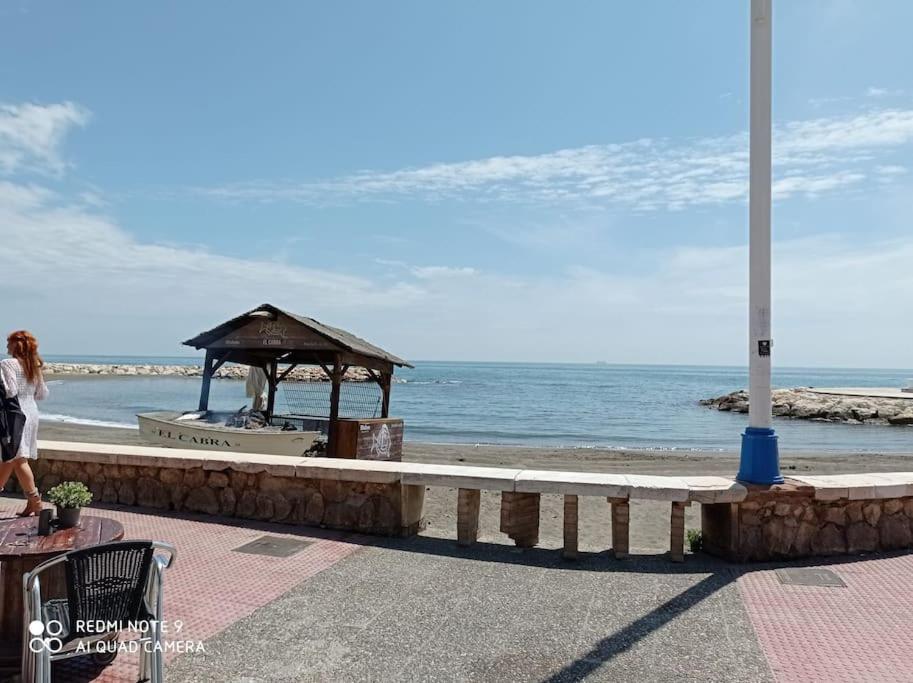 a woman standing next to the ocean with a gazebo at MALAGA BEACH, PEDREGALEJO Apt.4/6 2 Hab. in Málaga