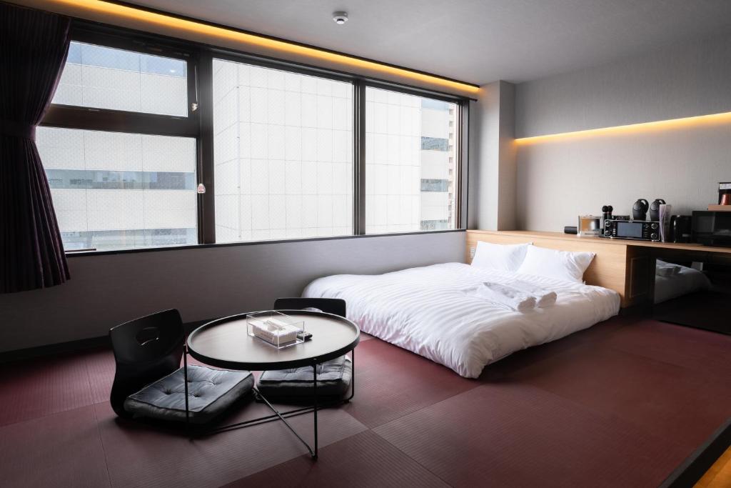 una camera con un letto bianco e un tavolo di ピンポンホテル&キャビン pin pon hotel & cabin a Shunan